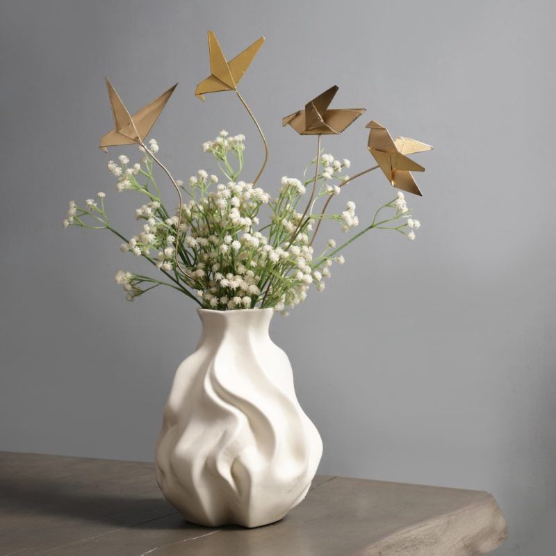 A wider view of the golden origami bird metal sticks displayed in a white artistic vase, styled with delicate white flowers for a chic home accent.