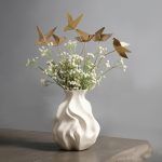 A set of 6 golden origami birds on bendable metal stems arranged with greenery and white florals, blending seamlessly into a minimalist and modern décor style.