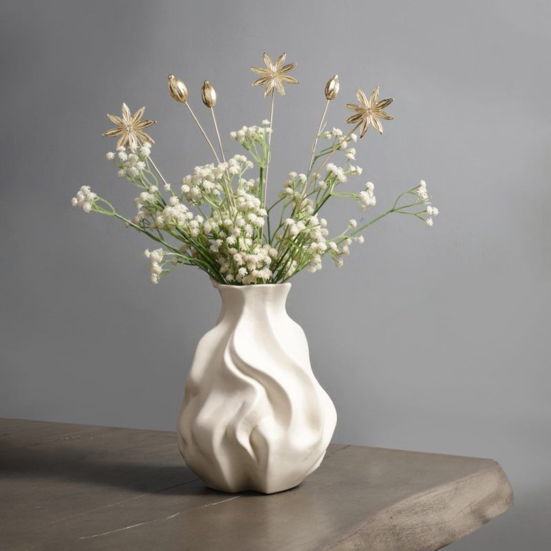 A styled shot of Golden Spice Metal Sticks placed in a sculptural white vase on a wooden table, blending seamlessly with modern and minimalist home décor.