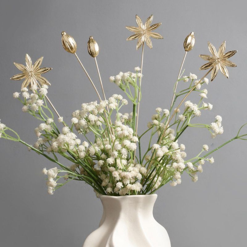 A close-up of Golden Spice Metal Sticks arranged in a vase with white baby’s breath flowers, highlighting their elegant gold finish and unique spice-inspired design.