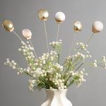 A close-up shot of set of 6 golden and golden-white seashells, showing their textured surface and elegant gold finish on bendable stems.