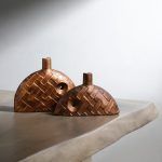 A set of two brown ceramic bud vases with a woven texture design, displayed on a neutral-toned table. One vase is slightly larger than the other, with a small circular cutout detail. Brand: Glimpse Homes.