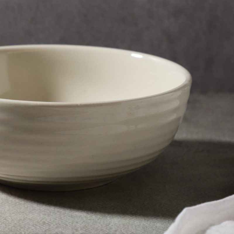 Close-up of a glossy white ceramic bowl, showcasing its smooth glaze and subtle textured details.