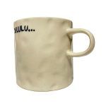 white background image of an off-white, textured ceramic mug. The mug has the word “DELULU…” printed in bold black letters.