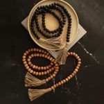 Farmhouse wooden bead garlands in natural and black finishes with jute tassels, rustic home decor accents.