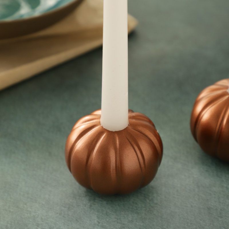 Close-up of rose gold pumpkin candle holder base with taper candle.
