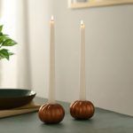 Pair of rose gold pumpkin candle holders with lit taper candles for table decor.