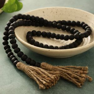 Farmhouse wooden bead garland in black finish with jute tassels in ceramic bowl.