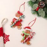 Flat lay arrangement of the Christmas tree gingerbread ornaments set of 2 placed on a beige surface with festive props including pine cones, berries, and a red snowflake.