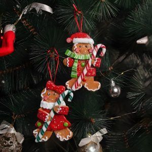 Christmas tree gingerbread ornaments set of 2 hanging on green pine branches, featuring a male and female gingerbread figure in festive red attire.
