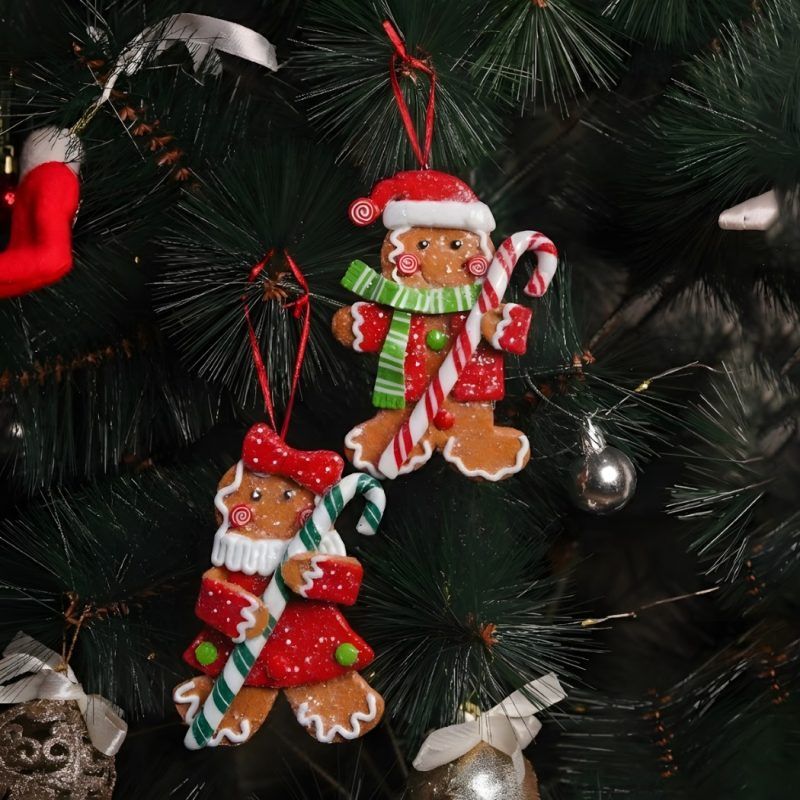 Christmas tree gingerbread ornaments set of 2 hanging on green pine branches, featuring a male and female gingerbread figure in festive red attire.