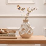 Golden Persian charm metal sticks set of 3 (Hamsa, Eye, and Crescent Moon) arranged in a white vase with dried flowers on a wooden table.