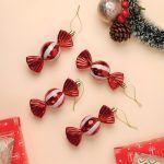 Top view of Red & White Toffee Christmas Tree Ornaments (Pack of 4) arranged on a beige background with festive gift wrapping and pine cones.
