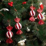 Red & White Toffee Christmas Tree Ornaments hanging on a green pine tree surrounded by festive berries and decor.