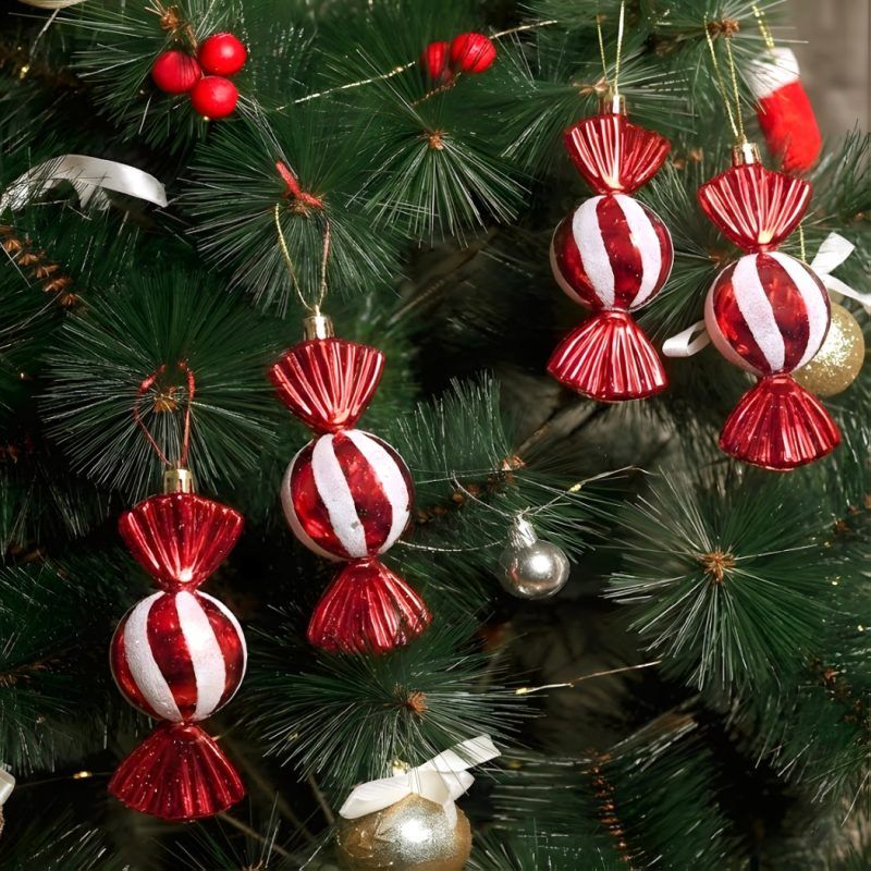 Red & White Toffee Christmas Tree Ornaments hanging on a green pine tree surrounded by festive berries and decor.