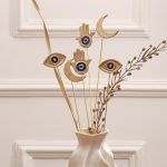 Close-up detail of the Persian Charm set of 6 mixed with dried flowers, highlighting the interplay between the gold metal and natural textures.