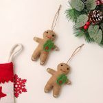 Flat lay of soft felt gingerbread decorations featuring green holly leaves and red stitching details.