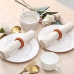 Elegant table setting for two featuring textured rust yarn napkin rings, perfect for autumn or warm-toned dining.