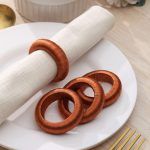 Close-up detail of burnt orange yarn-wrapped napkin rings stacked next to a white linen napkin.