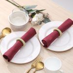 Elegant dinner setting for two featuring rustic green yarn napkin holders on burgundy cloth napkins.