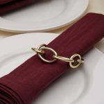 Close-up detail of a champagne gold metal knot napkin ring showing the chain link design and high-quality finish.