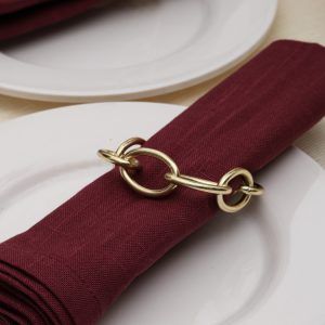Close-up detail of a champagne gold metal knot napkin ring showing the chain link design and high-quality finish.