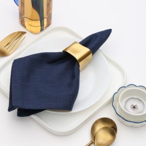 Elegant table setting featuring a Glimpse Homes Golden Cuff Napkin Ring paired with gold cutlery and a candle, ideal for wedding decor.