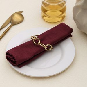 Modern champagne gold napkin holder on a white plate with gold cutlery for a festive Indian dining setup.