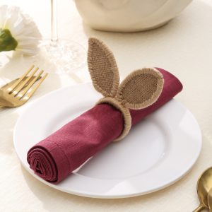 Close-up of a rustic jute bunny ear napkin ring holding a maroon napkin, ideal for Easter table settings.