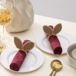 A pair of festive bunny ear napkin rings arranged on dinner plates for a spring-themed dining experience.