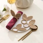 Set of four handmade jute bunny ear napkin rings arranged on a plate to showcase the textured woven design.