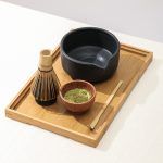 Glimpse Homes matte black ceramic matcha bowl and whisk holder displayed on a wooden tray (bamboo whisk and scoop are props).