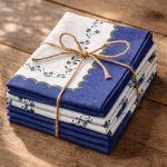 A set of Glimpse Homes 100% cotton Blue Meadow napkins stacked and tied with jute twine, showcasing the blue scalloped details.