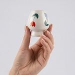 Close-up of a hand holding the ceramic whisk holder with floral bloom tulip design by Glimpse Homes.