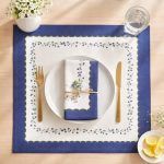 Overhead shot of a farmhouse-style place setting featuring a Glimpse Homes Blue Meadow Napkin tied with string on a white plate.