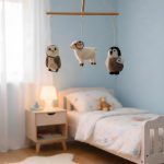 Glimpse Homes hanging baby mobile with felt animals suspended from a wooden frame above a nursery bed.