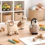 Set of three Glimpse Homes felt animals sitting on a wooden playroom table surrounded by crayons and wooden blocks.