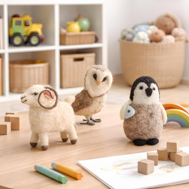 glimpse-homes-kids-playroom-felt-decor-set-of-3 Set of three Glimpse Homes felt animals sitting on a wooden playroom table surrounded by crayons and wooden blocks.