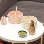 Collection of Glimpse Homes matte pink and cream speckled ceramic matcha bowls and whisk holders arranged together, showcasing the unique double-ring design.