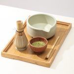 Glimpse Homes matte mint green ceramic matcha bowl and whisk holder displayed on a wooden tray (bamboo whisk is a prop).
