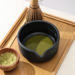 Freshly prepared green matcha tea showing vibrant color inside a matte black ceramic bowl with pouring spout by Glimpse Homes.