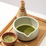 Freshly whisked green matcha tea inside a matte mint green ceramic bowl with pouring spout by Glimpse Homes.