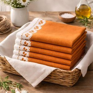 A stack of folded Terracotta Bloom cotton napkins by Glimpse Homes in a basket, highlighting the smooth printed edge.