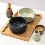 Angled view of the Glimpse Homes ribbed ceramic matcha bowl collection featuring both matte black and mint green options with whisk holders.