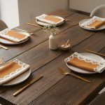 Wooden dining table set with multiple Glimpse Homes Terracotta Bloom printed napkins ready for a family dinner.