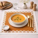 Glimpse Homes Terracotta Bloom printed table linen styled underneath a soup bowl, showcasing the rust color and pattern.