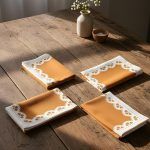 Set of 4 Glimpse Homes Terracotta Bloom napkins folded and displayed separately on a wooden table to show color consistency.