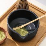 Top-down view of a Glimpse Homes matte black ceramic bowl containing green matcha powder, highlighting the dark interior finish.