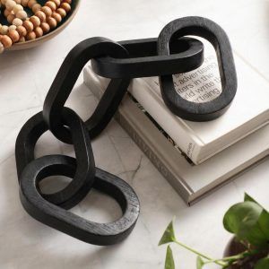 Glimpse Homes black 5 knot wooden chain styled over stacked coffee table books on a marble countertop.