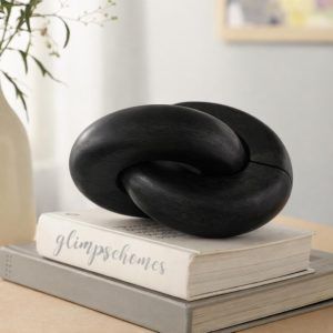 A black wooden chain with 2 knots by Glimpse Homes, styled as chic coffee table decor resting on a white book.